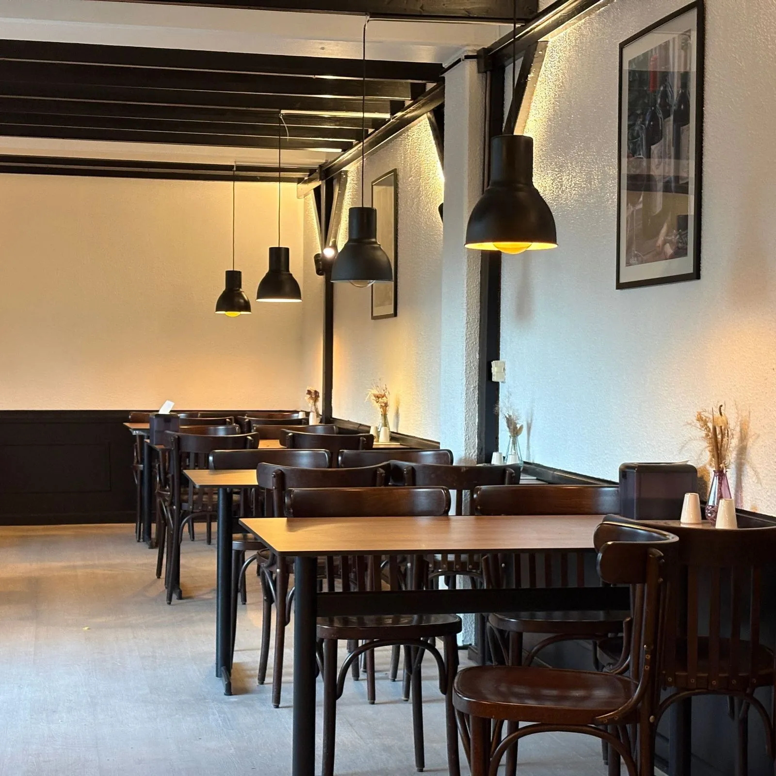Restauranten hos Bella Pizza med borde, stole og varmt lys under de sorte bjælker